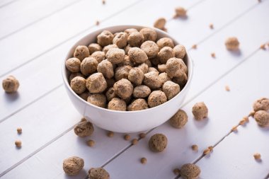 Çiğ Soya Parçacıkları, vejetaryenler için soya eti renkli arka planda bir kasede ya da yığın halinde izole edilmiş.