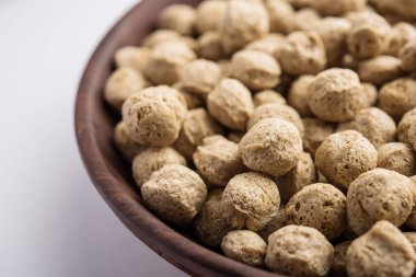 Çiğ Soya Parçacıkları, vejetaryenler için soya eti renkli arka planda bir kasede ya da yığın halinde izole edilmiş.