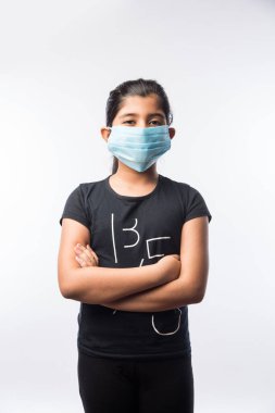 Hintli Kız Çocuk Kirliliğe karşı güvenlik önlemi olarak Sağlık Yüzü Maskesi Giyiyor veya Virüs Yayılıyor, beyaz arka plana karşı izole olarak ayakta duruyor