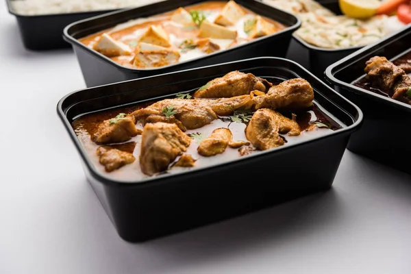 Online Food delivery concept Indian paneer butter masala and palak paneer, mutton & chicken curry with roti and rice in plastic containers, food like butter chicken, chicken
