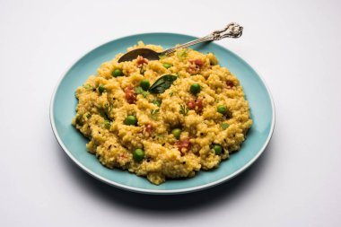 Sebze Dalia veya Daliya Khichadi veya Kırık Buğday Khichdi domates, yeşil bezelye ve biberli, bir kase veya tabakta servis edilir.