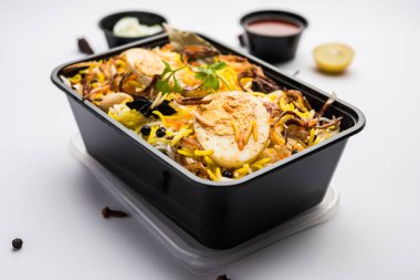 Restoran stili Egg Biryani veya Anda Pulao Raita ve Salan ile birlikte plastik kutu veya konteynırda eve teslim edilmek üzere paketlendi