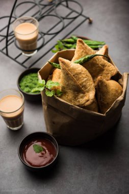 Samosa - Üçgen şeklinde kızarmış / fırında hamur işi, lezzetli dolgulu, popüler Hint çay saati atıştırmalıkları, yeşil turşu, domates ve ketçap ile servis edilen