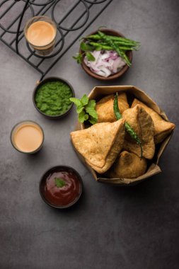 Samosa - Üçgen şeklinde kızarmış / fırında hamur işi, lezzetli dolgulu, popüler Hint çay saati atıştırmalıkları, yeşil turşu, domates ve ketçap ile servis edilen
