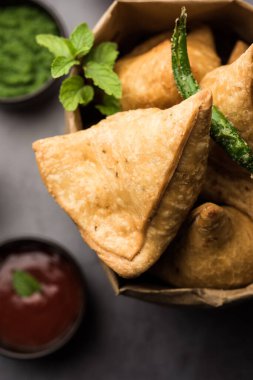 Samosa - Üçgen şeklinde kızarmış / fırında hamur işi, lezzetli dolgulu, popüler Hint çay saati atıştırmalıkları, yeşil turşu, domates ve ketçap ile servis edilen