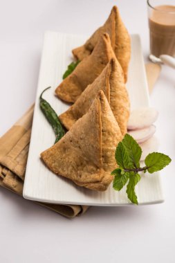 Samosa - Üçgen şeklinde kızarmış / fırında hamur işi, lezzetli dolgulu, popüler Hint çay saati atıştırmalıkları, yeşil turşu, domates ve ketçap ile servis edilen