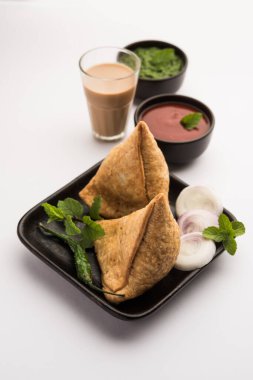 Samosa - Üçgen şeklinde kızarmış / fırında hamur işi, lezzetli dolgulu, popüler Hint çay saati atıştırmalıkları, yeşil turşu, domates ve ketçap ile servis edilen