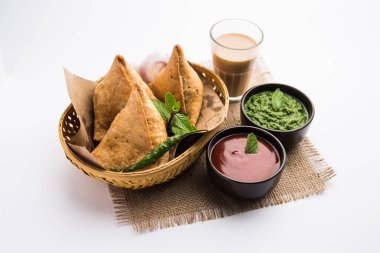 Samosa - Üçgen şeklinde kızarmış / fırında hamur işi, lezzetli dolgulu, popüler Hint çay saati atıştırmalıkları, yeşil turşu, domates ve ketçap ile servis edilen
