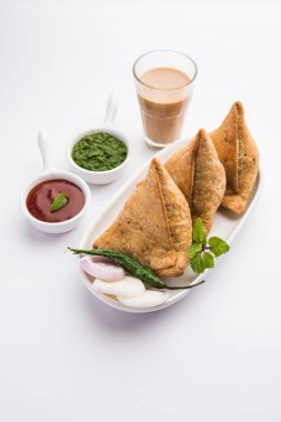 Samosa - Üçgen şeklinde kızarmış / fırında hamur işi, lezzetli dolgulu, popüler Hint çay saati atıştırmalıkları, yeşil turşu, domates ve ketçap ile servis edilen