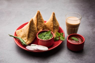 Samosa - Üçgen şeklinde kızarmış / fırında hamur işi, lezzetli dolgulu, popüler Hint çay saati atıştırmalıkları, yeşil turşu, domates ve ketçap ile servis edilen