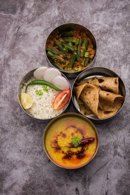 Ofis veya işyeri için paslanmaz çelikten yapılmış Hint vejetaryen beslenme çantası veya Tiffin, Dal Fry, Bhindi Masala, chapati ve salatalı pirinç içerir.