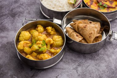 Ofis veya işyeri için paslanmaz çelikten yapılmış Hint vejetaryen beslenme çantası veya Tiffin, Dal Fry, Gobi Masala, chapati ve salatalı pilav içerir.