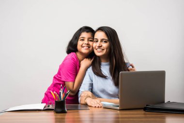 Çalışan Hintli anne, çocuk salgınında evde çalışıyor. Dizüstü bilgisayar kullanan bir kadın ve sevimli çocuk. Rahat evdeki Freelancer işyeri. Mutlu anne ve kız.
