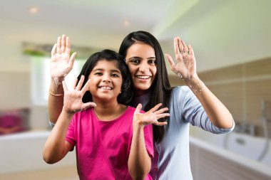 Sevimli küçük bir Hintli kız ve güzel annesi ellerini yıkıyorlar. Enfeksiyon ve virüslere karşı koruma