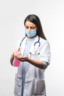 Dezenfeksiyon ve el yıkama - üniformalı ve yüz maskeli Hintli kadın doktor ellerine dezenfektan ya da dezenfektan koyar. Coronavirus covid-19 'a karşı koruma