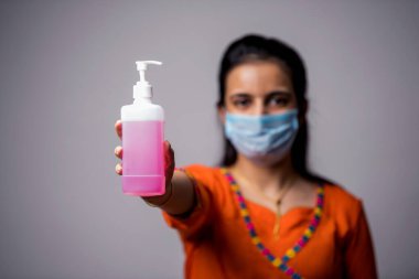 Tıbbi maske takan, elleri dezenfekte eden Hintli kız. Eller antiseptiği yıkar. Corona Virüsü Konsepti