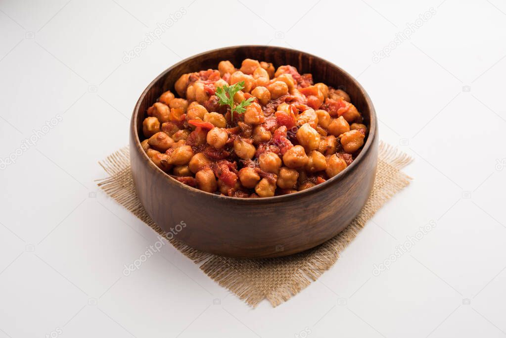Spicy Chickpea curry, Chana Masala or Choley in bowl with chapati and salad. Traditional North Indian dish.