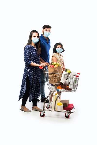 Indian Family Shopping with kids during virus outbreak. Mother, father and daughter wearing surgical face mask buying grocery in supermarket. Family in shop.