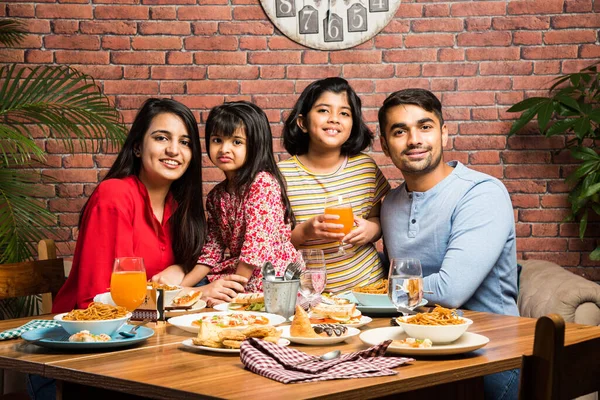 Evde ya da restoranda yemek yiyen dört kişilik Hintli bir aile. Güney Asyalı anne, baba ve iki kız birlikte yemek yiyorlar.