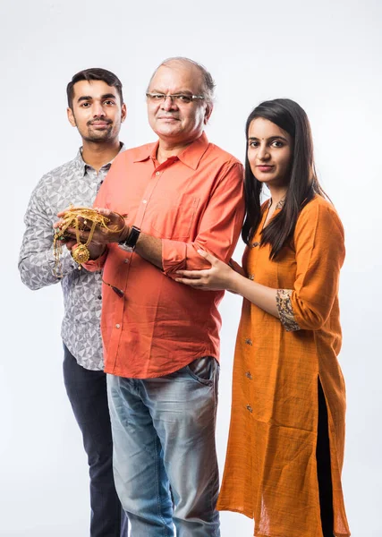 Indian old man with young son and daughter or couple holding gold jewelry, ornaments - Asset or Gold Loan concept