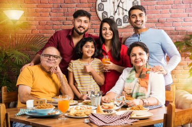 Hindistan 'ın çok nesilli ailesi yemek masasında yemek yiyor. Güney Asyalı büyükbaba, anne, baba ve iki kız birlikte yemek yiyorlar.