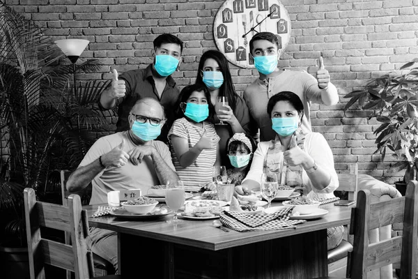 Indian family wears face mask while eating food in restaurant after corona pandemic unlock - concept showing new normal lifestyle in India