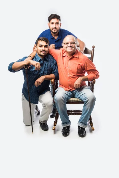 Indian old man or father with young son and daughter, sitting over rocking chair