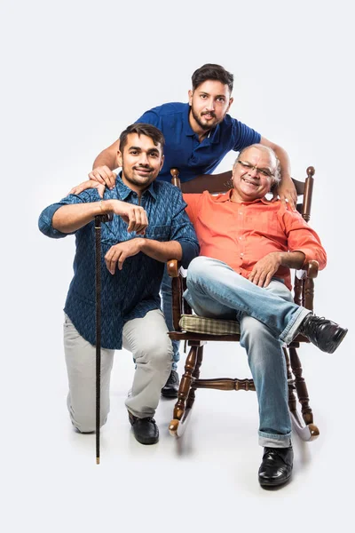 Indian old man or father with young son and daughter, sitting over rocking chair