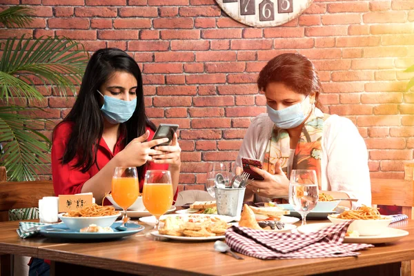 Indian asian friends Eating in Restaurant Dining Concept wearing protective face mask after corona pandemic