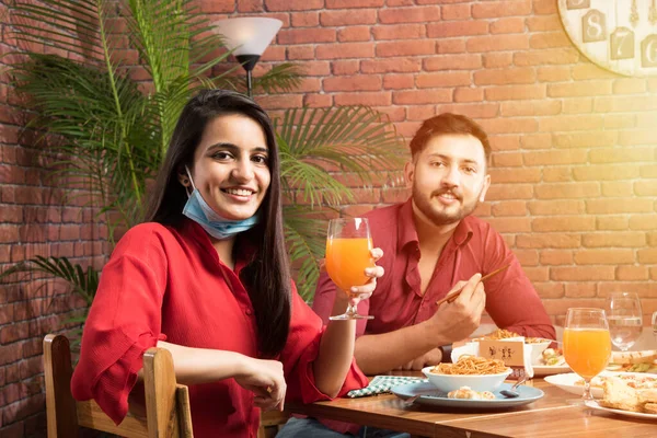 Indian asian friends Eating in Restaurant Dining Concept wearing protective face mask after corona pandemic