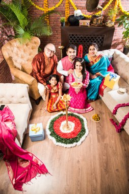 Ganesh Festivali 'ni ya da Chaturthi' yi kutlayan mutlu Hint Ailesi - Hoş geldiniz ya da Pooja 'yı sahneleyen ve geleneksel olarak Marigold Çiçekleri ile süslenmiş evde şekerleme yiyen
