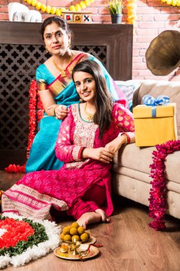 Ganesh Festivali 'ni ya da Chaturthi' yi kutlayan mutlu Hint Ailesi - Hoş geldiniz ya da Pooja 'yı sahneleyen ve geleneksel olarak Marigold Çiçekleri ile süslenmiş evde şekerleme yiyen