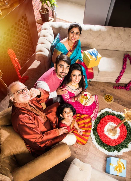 Ganesh Festivali 'ni ya da Chaturthi' yi kutlayan mutlu Hint Ailesi - Hoş geldiniz ya da Pooja 'yı sahneleyen ve geleneksel olarak Marigold Çiçekleri ile süslenmiş evde şekerleme yiyen