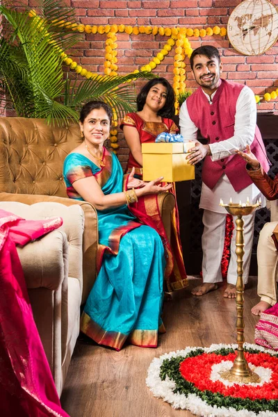 Ganesh Festivali 'ni ya da Chaturthi' yi kutlayan mutlu Hint Ailesi - Hoş geldiniz ya da Pooja 'yı sahneleyen ve geleneksel olarak Marigold Çiçekleri ile süslenmiş evde şekerleme yiyen