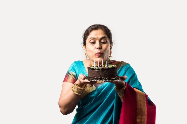 Indian beautiful old woman or lady celebrating birthday with chocolate cake while wearing ethnic wear