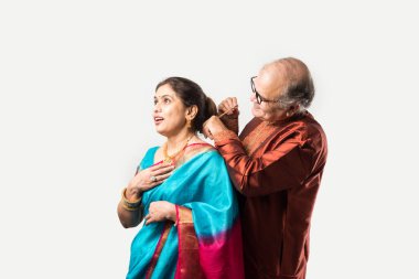 Hintli yaşlı adam doğum gününde, sevgililer gününde, yıldönümünde ya da Diwali festivalinde güzel karısına altın kolye takıyor ya da sunuyor.