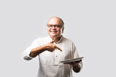 Yaşlı ya da yaşlı Hintli bir adam kaşıkla çatal kullanarak boş beyaz tabak ya da kâseden yemek yiyor. Beyaz arka planda farklı ifadelerle tek başına duruyor.