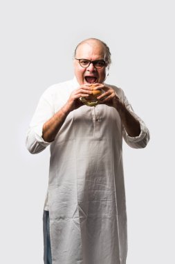 Hint ihtiyarı hamburger ya da mango suyu ya da soğuk içecek ile hamburger yiyor.