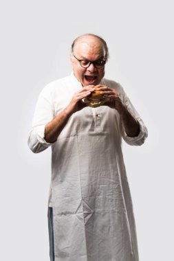 Hint ihtiyarı hamburger ya da mango suyu ya da soğuk içecek ile hamburger yiyor.