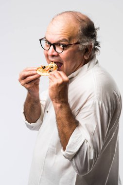 Beyaz arka planda tek başına dururken pizza yiyen yaşlı ya da yaşlı Hintli bir adam.