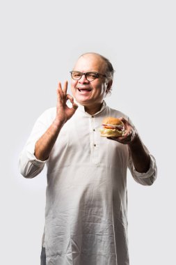 Hint ihtiyarı hamburger ya da mango suyu ya da soğuk içecek ile hamburger yiyor.