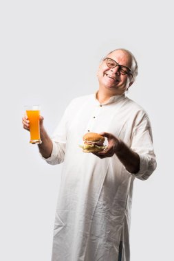 Hint ihtiyarı hamburger ya da mango suyu ya da soğuk içecek ile hamburger yiyor.