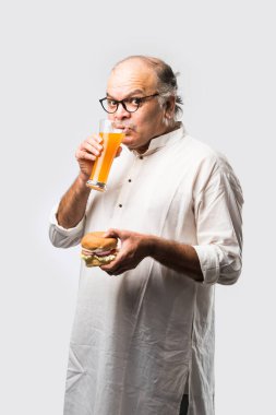 Hint ihtiyarı hamburger ya da mango suyu ya da soğuk içecek ile hamburger yiyor.