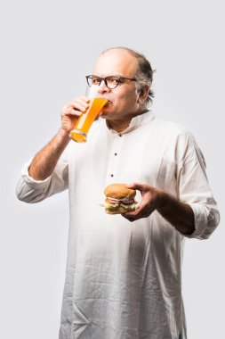 Hint ihtiyarı hamburger ya da mango suyu ya da soğuk içecek ile hamburger yiyor.