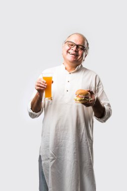 Hint ihtiyarı hamburger ya da mango suyu ya da soğuk içecek ile hamburger yiyor.
