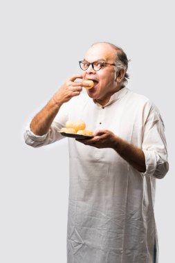 Hintli yaşlı adam panipuri, phuchka, gupchup veya golgappa yer.