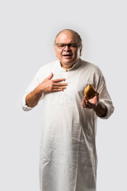 Hintli yaşlı adam ya da kıdemli adam samosa ya da sebzeli börek yiyor.