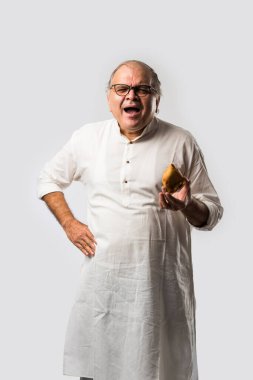 Hintli yaşlı adam ya da kıdemli adam samosa ya da sebzeli börek yiyor.