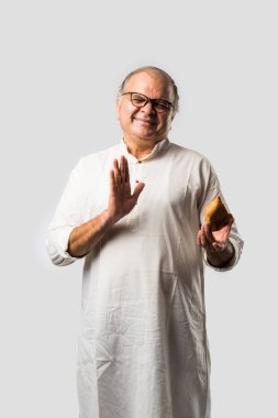 Hintli yaşlı adam ya da kıdemli adam samosa ya da sebzeli börek yiyor.