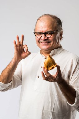 Hintli yaşlı adam ya da kıdemli adam samosa ya da sebzeli börek yiyor.